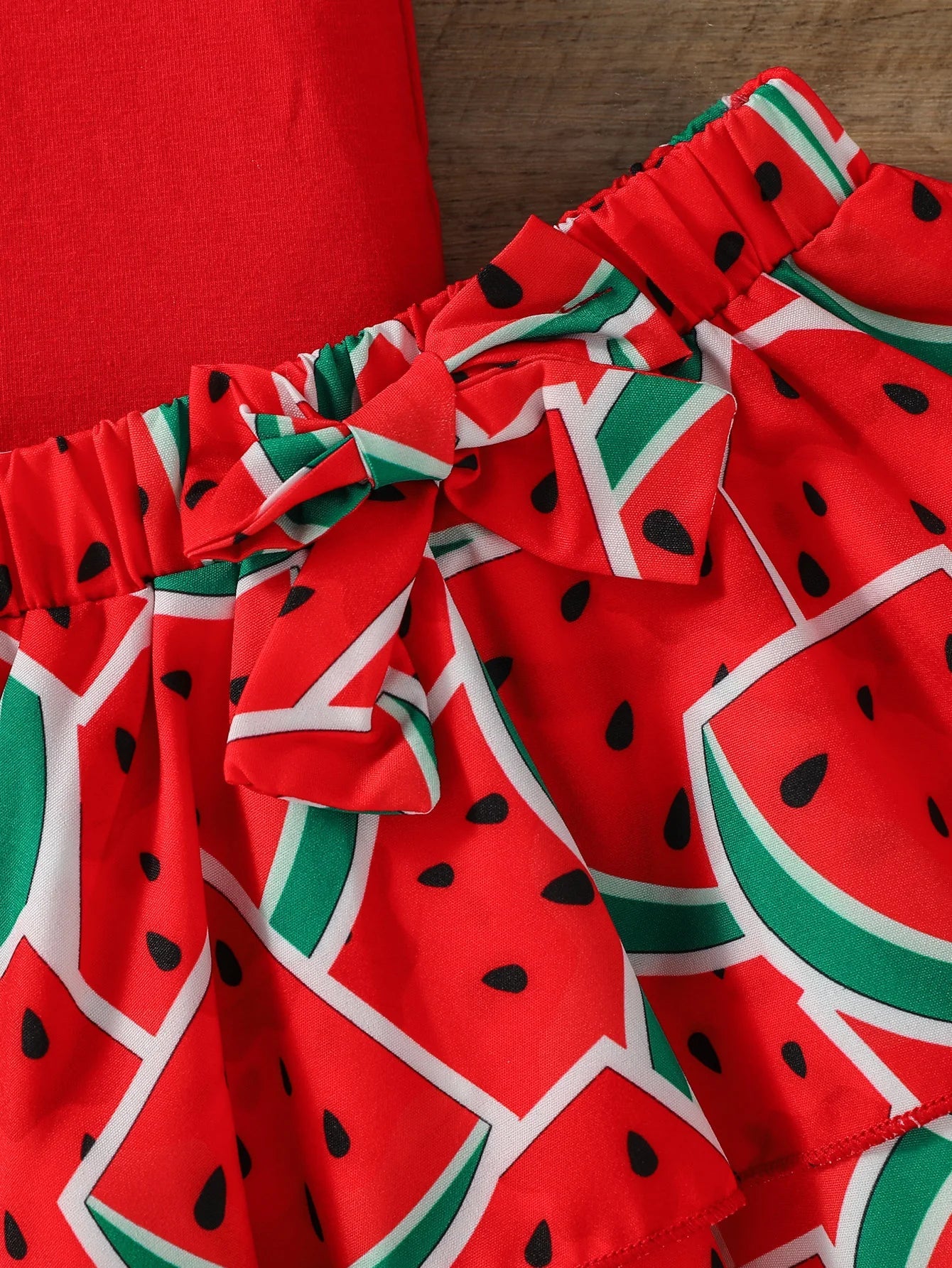 Detail of the soft fabric and vibrant watermelon print on a baby girl's summer outfit