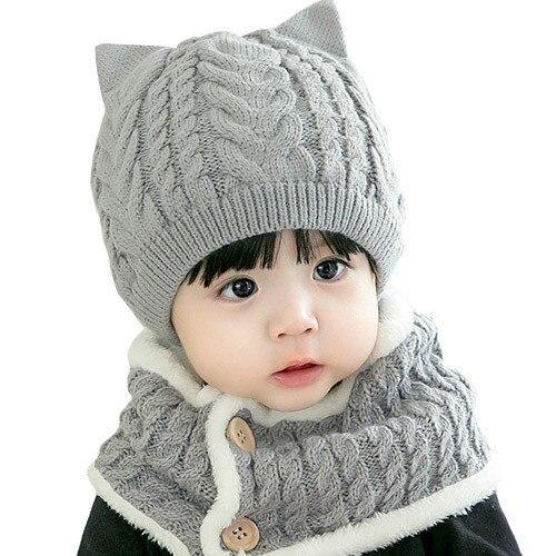 Full view of a baby modeling a warm knitted cat hat and scarf set, great for winter outdoor play.