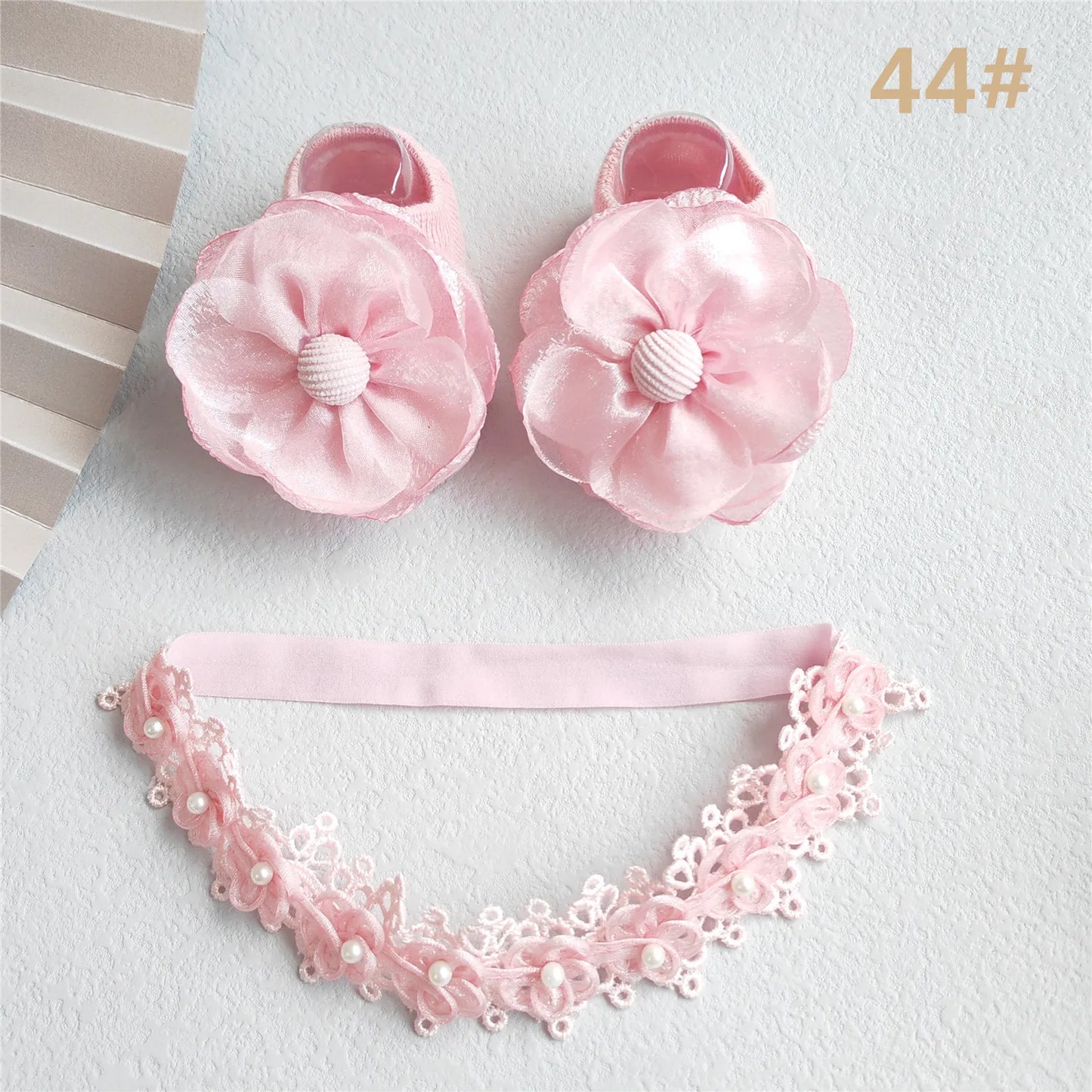 Baby girl gift set packaging showing a lace bow headband and pink cotton socks, 0-12 months