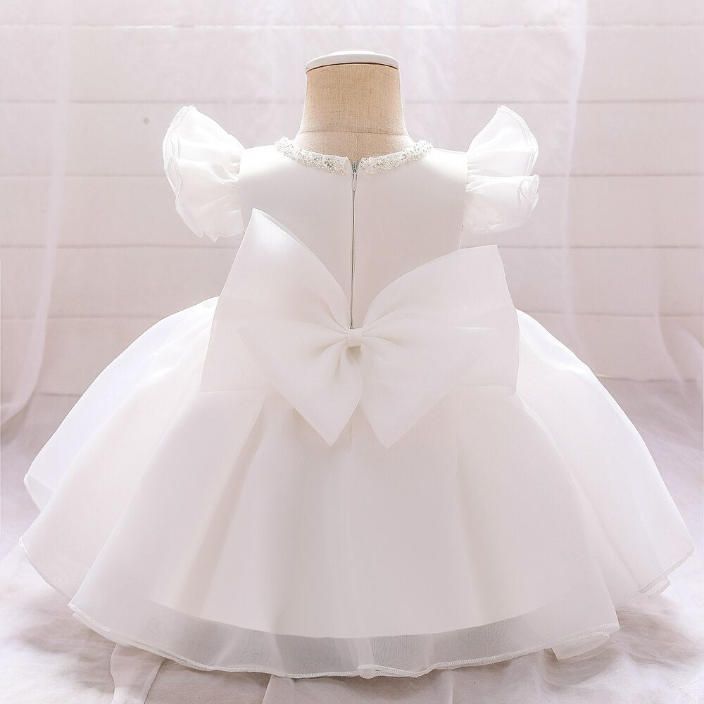 Collection of baby girl princess dresses in various colors with beaded necklines and big bows.