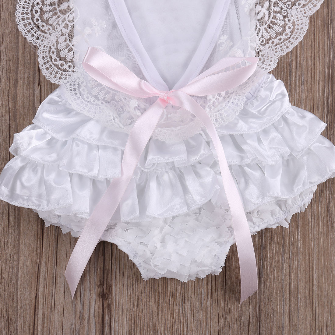 Back view of a baby girl's white lace bodysuit dress, showcasing intricate lace detail and comfortable cotton.