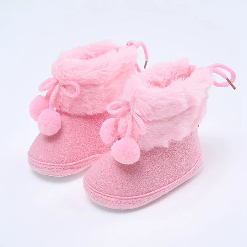 Overhead shot of pink baby girl's winter snow booties with fluff ball and soft sole