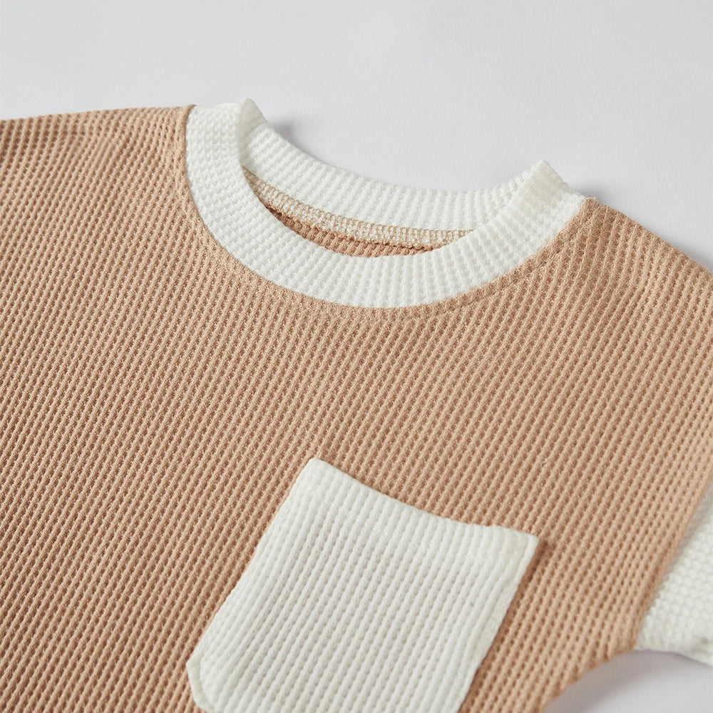 Flat lay of a short sleeve baby cotton waffle knit romper and a matching hat