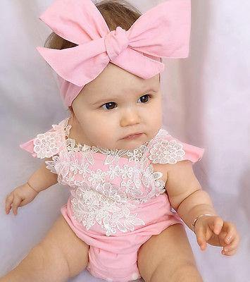 Close-up of pink baby romper fabric, showing intricate lace and a cute matching headband.