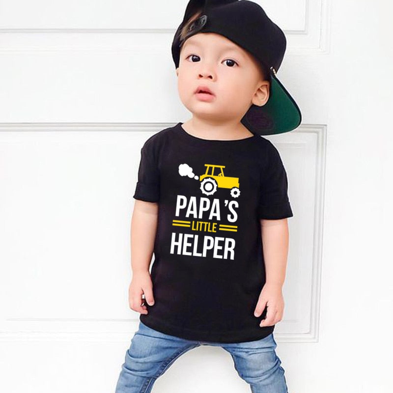 Happy dad and son showing off their new matching 'Papa' and 'Little Helper' casual cotton blend t-shirts.