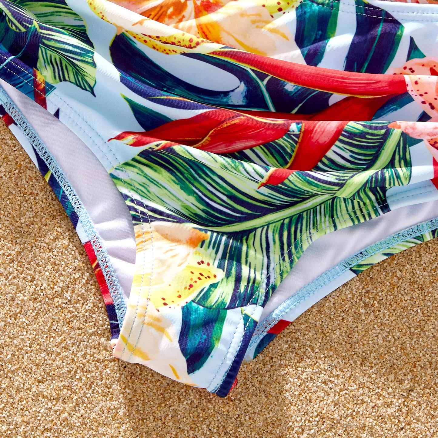 Family set of pink floral kids swimwear, women's swimwear, and men's swim trunks.