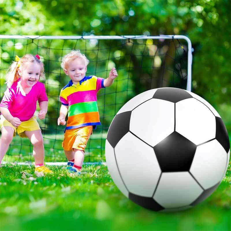 Family enjoying a kids party with a giant inflatable outdoor soccer ball on green grass