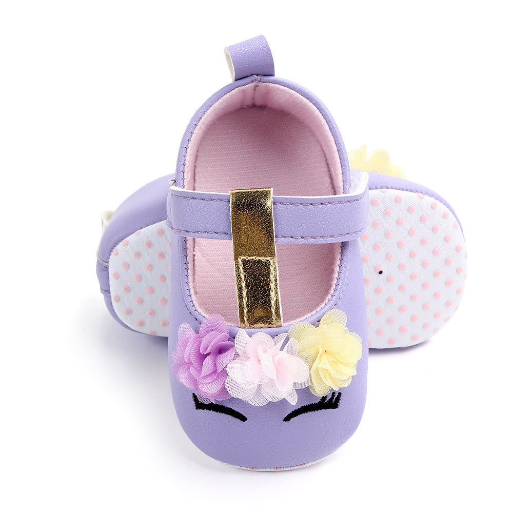 Close-up of girl's unicorn first walker shoes, floral accents, soft sole for early walking