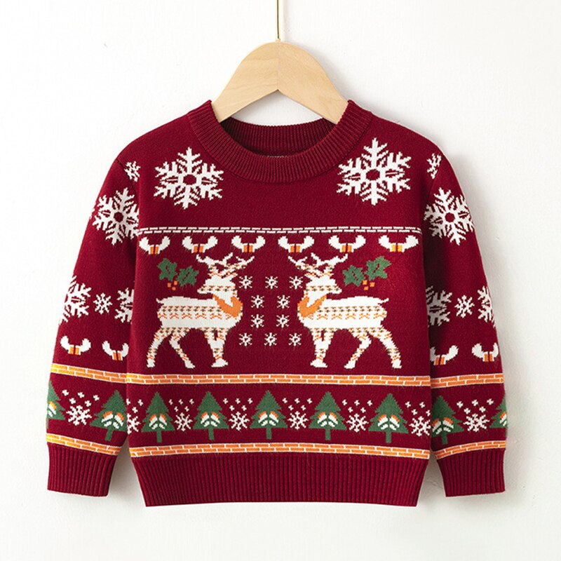 Flat lay of a red kids reindeer Christmas sweater with holiday decorations