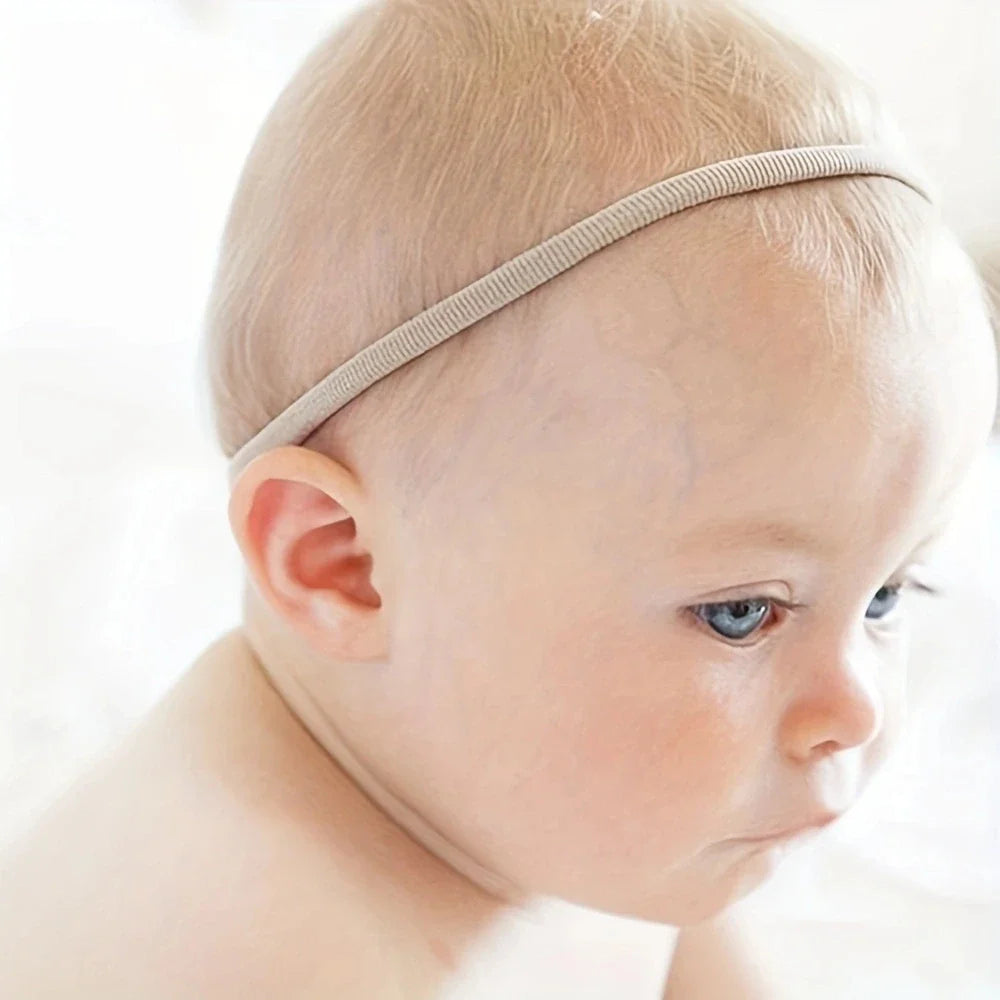 Close-up of a variety pack of 100 soft nylon headbands, essential baby fashion accessories.