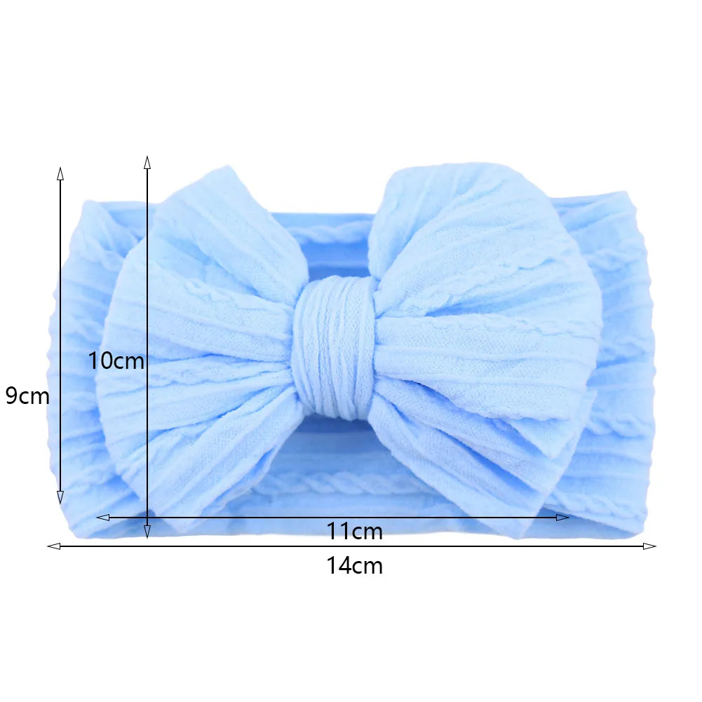 Model baby wearing a red cable bow headband, stylish hair accessory for infants