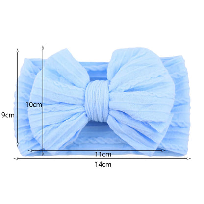 Model baby wearing a red cable bow headband, stylish hair accessory for infants