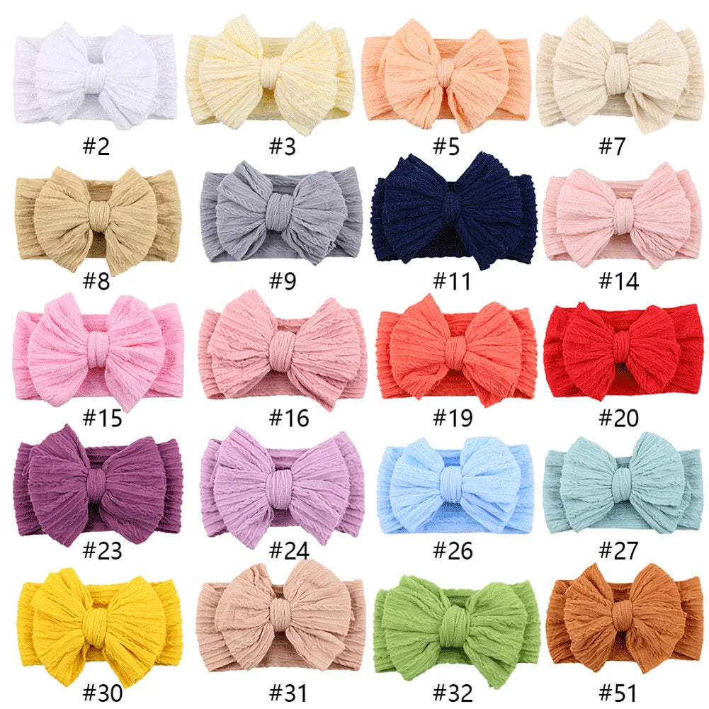 Overhead view of a baby wearing a green cable bow headband, soft newborn accessory
