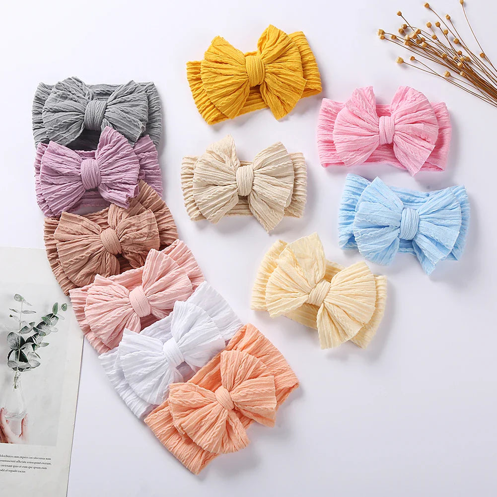 Side view of a baby girl wearing a pastel blue cable bow headband, cute baby fashion
