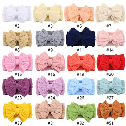 Hands holding a collection of 20pcs baby bow headbands, ideal for toddlers & infants