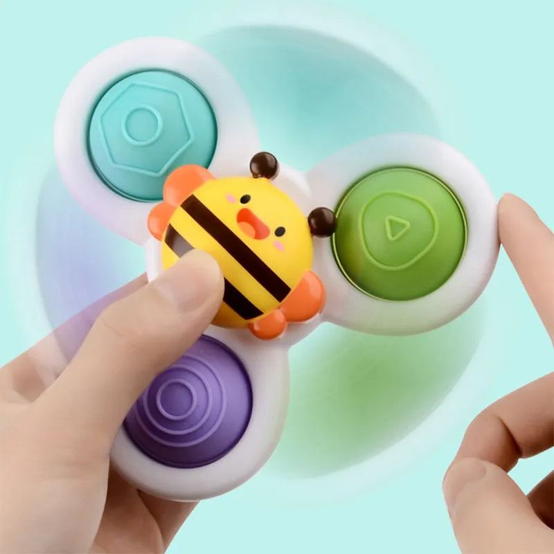 Infant playing with a suction cup spinning top attached to a high chair tray, learning toy