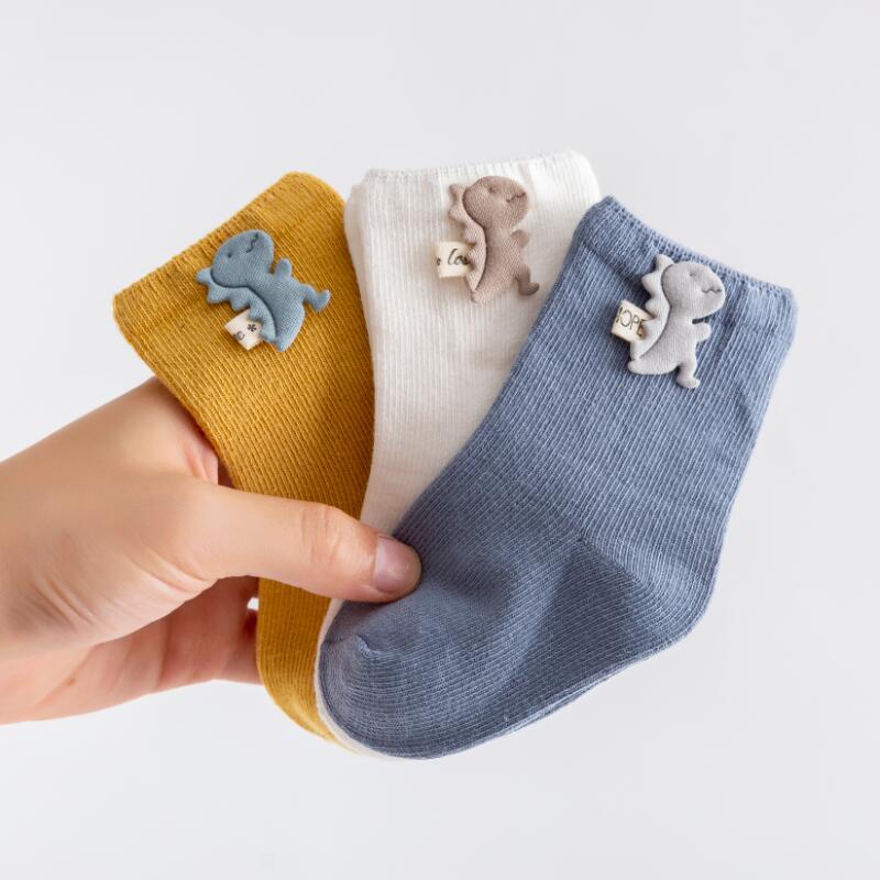3 pairs of soft cotton newborn socks, white, blue, and pink, on a clean surface.