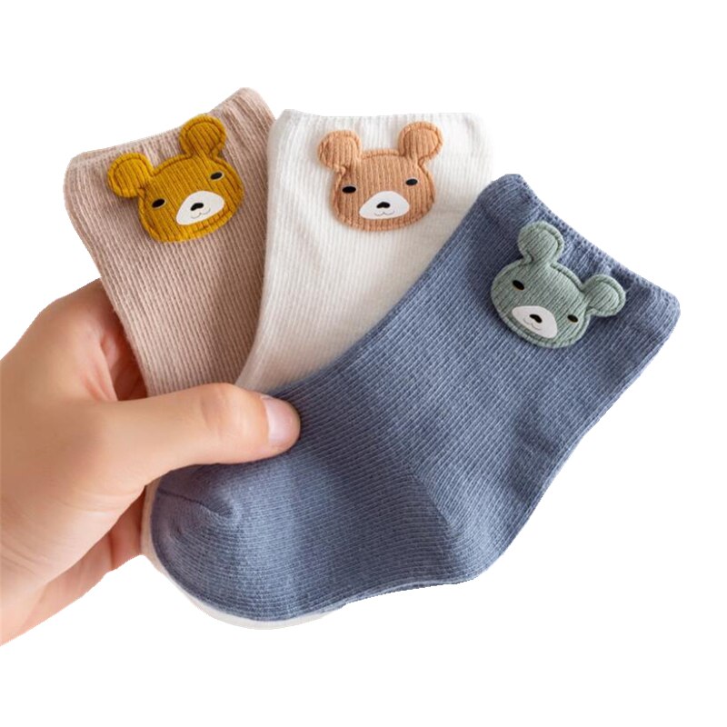 Three pairs of adorable cotton baby socks, essential baby clothing for newborns.