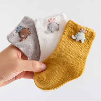 Infant apparel: three pairs of colorful cotton baby socks for newborns, neatly folded.