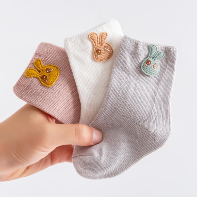 Soft cotton baby socks with elastic cuffs, shown in a pack of three for newborns.
