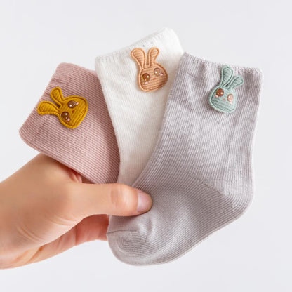 Soft cotton baby socks with elastic cuffs, shown in a pack of three for newborns.
