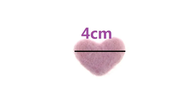 A newborn's tiny hand gently touching a soft wool love heart photography prop for baby pictures