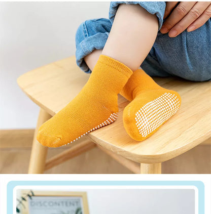 Kids anti-slip cotton socks on a child's foot on a slide, demonstrating non-skid grip for play