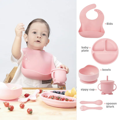 Durable children's silicone bib, divided plate, deep bowl, training cup, and two spoons, all in sage green.
