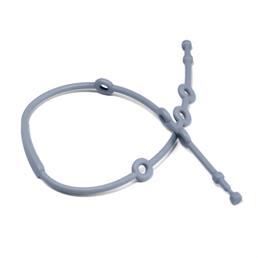 Infant exploring an adjustable silicone pacifier clip, indicating its use as a teether for oral development