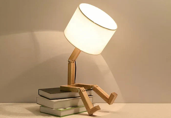 Functional wooden robot reading light with a poseable body and small storage shelf.