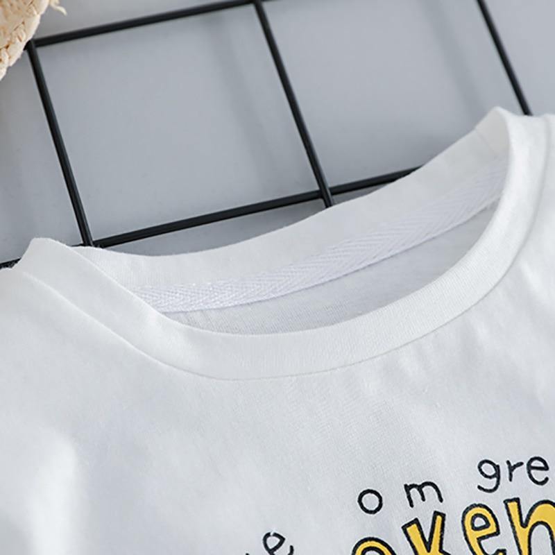 Closeup of a baby's smiling face wearing a white cactus print summer outfit, soft cotton blend.