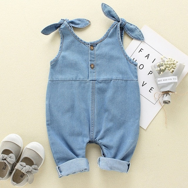 Baby girl in a stylish denim romper with delicate ruffle details, ideal for warm weather.