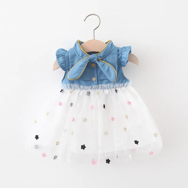 Adorable baby girl in a light blue denim bow dress with flying sleeves, perfect for summer.