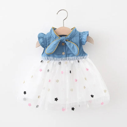 Adorable baby girl in a light blue denim bow dress with flying sleeves, perfect for summer.