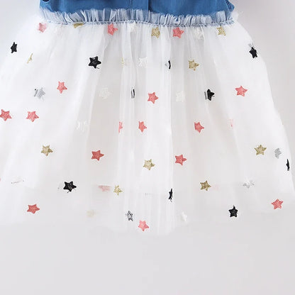 Detail of the soft denim fabric of a girls' dress, highlighting the bow and flying sleeves.