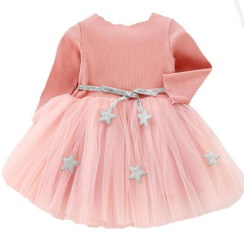Closeup of the star embellished mesh and soft cotton fabric of a long sleeve girls' party dress.