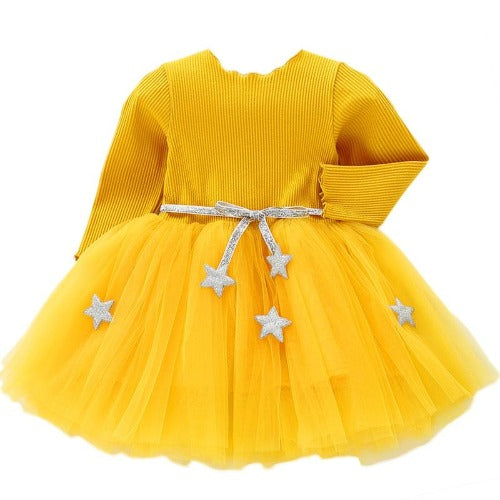 Toddler girl smiling in a festive long sleeve mesh star dress, ideal for holiday or birthday parties.