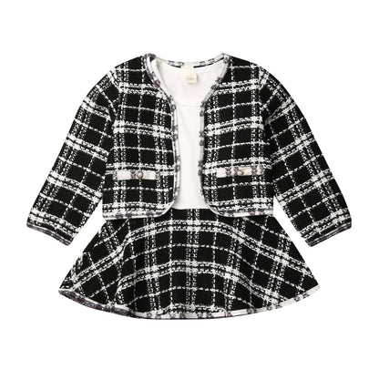 Full shot of a baby girl's party outfit featuring a plaid coat and tiered tutu dress