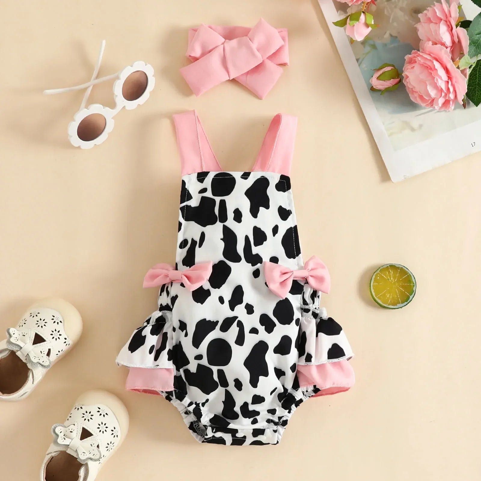 Cute infant girl bodysuit featuring a fun cow print design, paired with a matching bow headband.