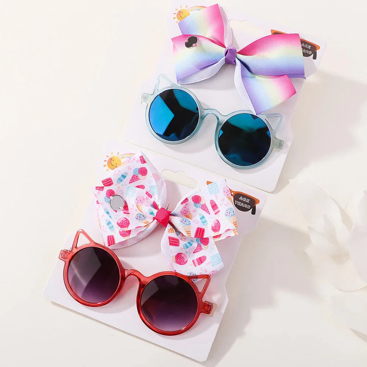 Infant girl's accessory kit: sweet hair bow and protective, stylish cartoon sunglasses.