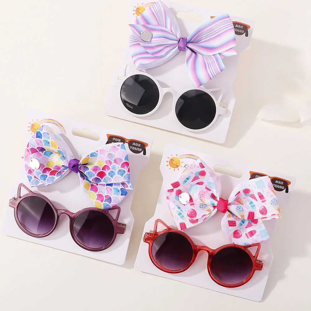 Stylish baby girl's accessory set: fun cartoon sunglasses & matching hair bow for toddlers.