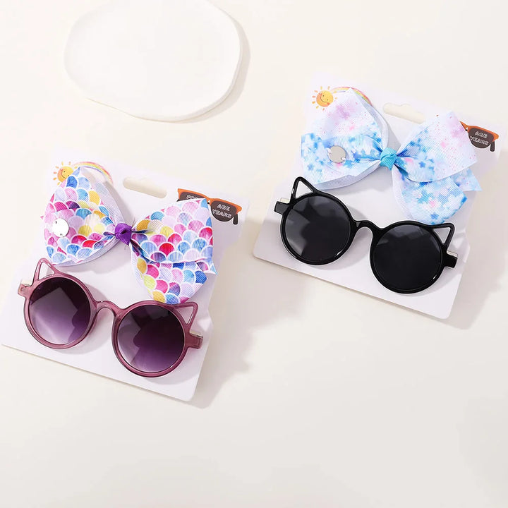 Baby girl's adorable bow with clip & playful cartoon sunglasses, ideal for sun protection.