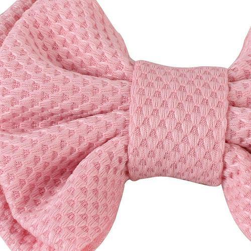 Close-up of the delicate bow detail on a baby girls' elastic headband.