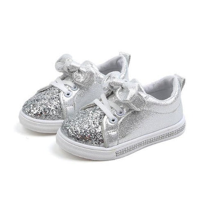 Pair of stylish infant girl's glitter sneakers with delicate bowknot, perfect for first steps.