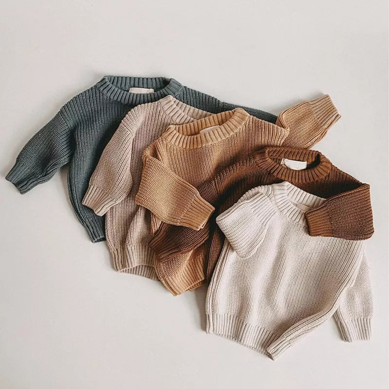 Adorable baby in a cozy knitted loose sweater, perfect for autumn winter warmth and comfort.