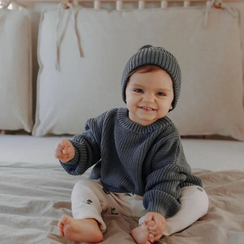 Close-up detail of the knit pattern on a baby's autumn winter loose sweater, highlighting softness.