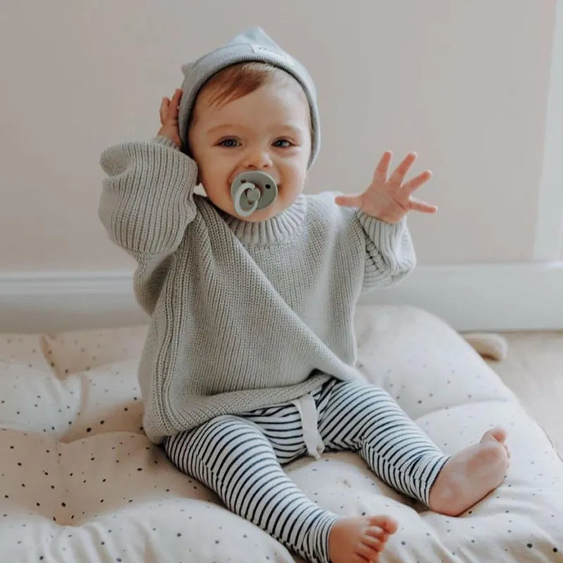 Baby modeling a comfortable loose-fit knitted sweater, essential for autumn winter baby fashion.