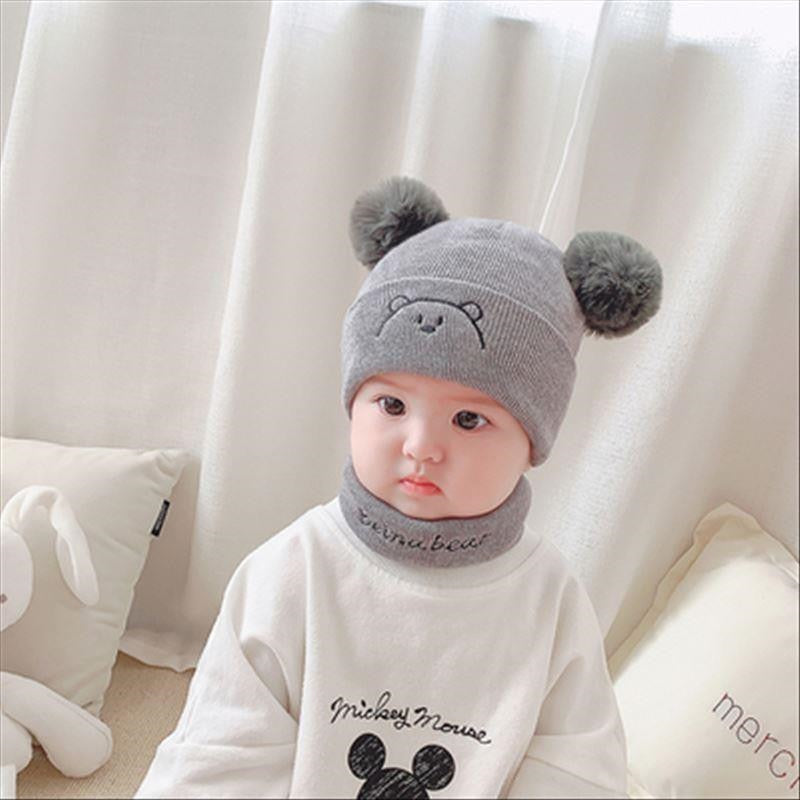 Adorable baby in a cozy white knit hat and matching scarf, perfect for winter warmth.