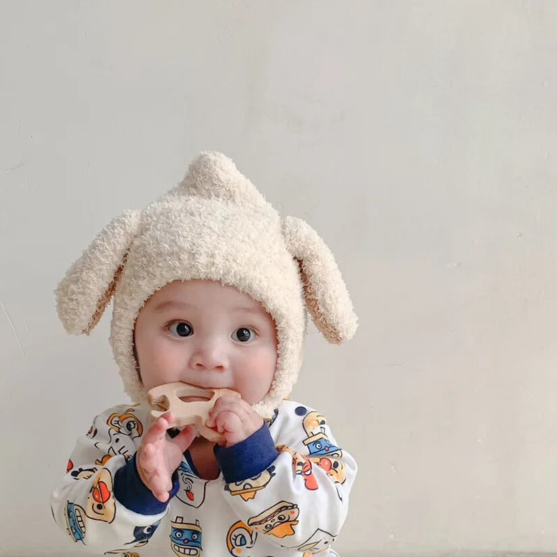 Smiling toddler in a cozy blue plush rabbit ears winter hat, ideal for cold weather.