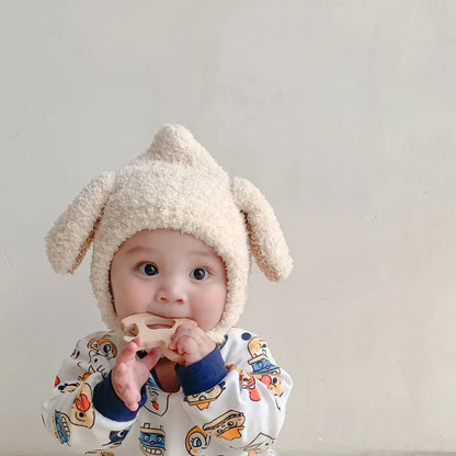 Smiling toddler in a cozy blue plush rabbit ears winter hat, ideal for cold weather.